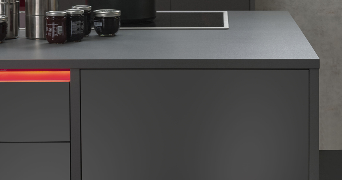 Detail černé pracovní desky s kuchyňskou skříňkou ve stejné barvě