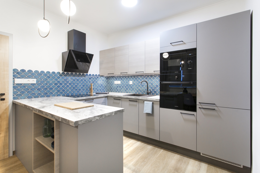 Kuchyň v minimalistickém hladkém pojetí v šedé barvě modelu Silk Touch v sestavě se světlým dekorem dřeva modelu EPIQA v barvě dekoru Nabucco.