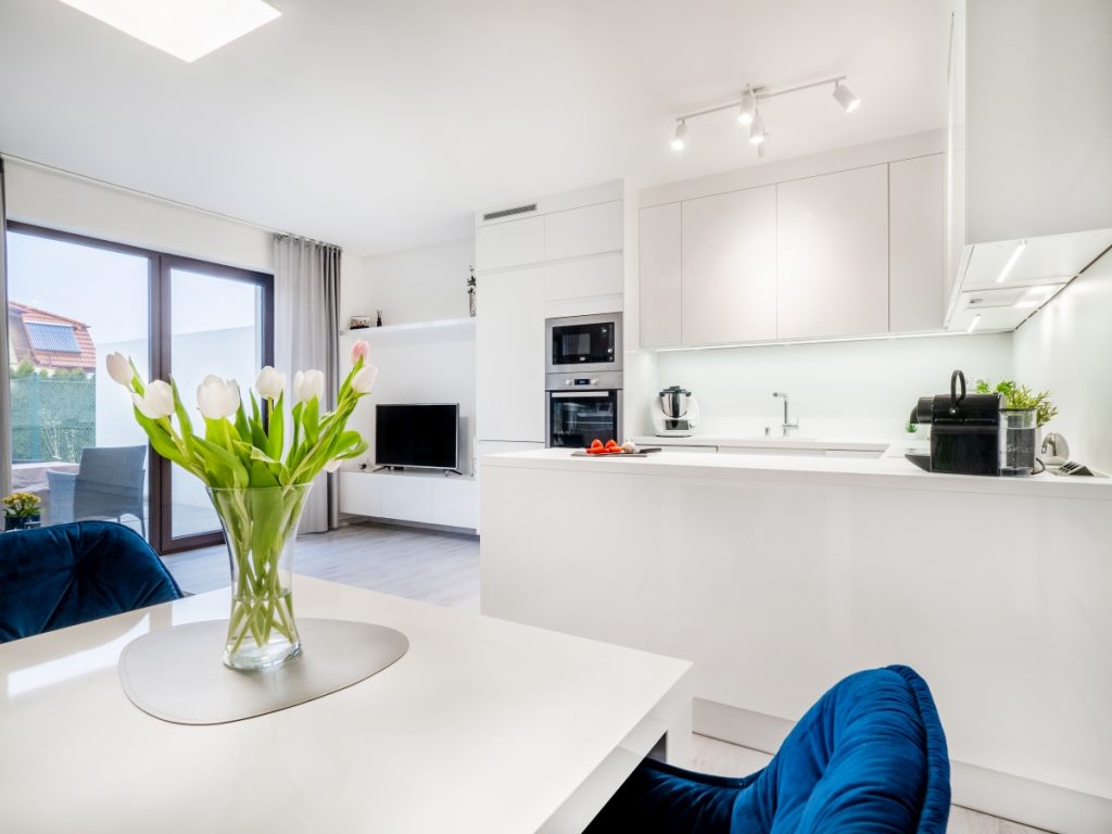 Moderní bílá kuchyně propojená s obývacím pokojem
