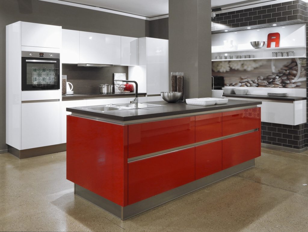 Lesklý ostrůvek v interiéru kuchyně v červené barvě.