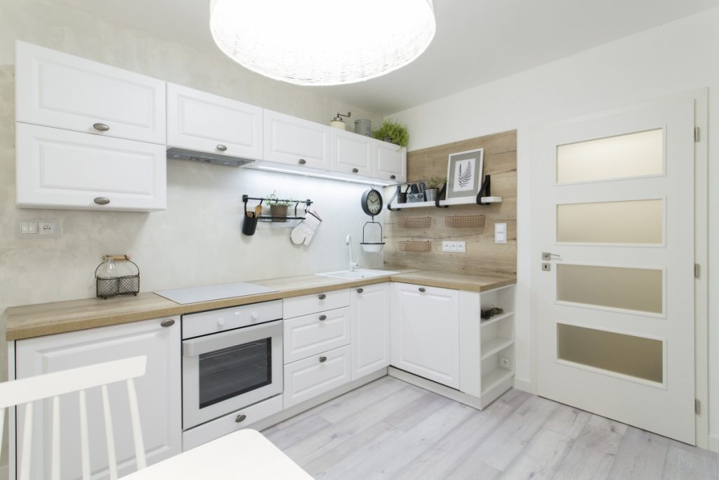 Provence kuchyně do bytu v bílé barvě s dřevěnou pracovní deskou.