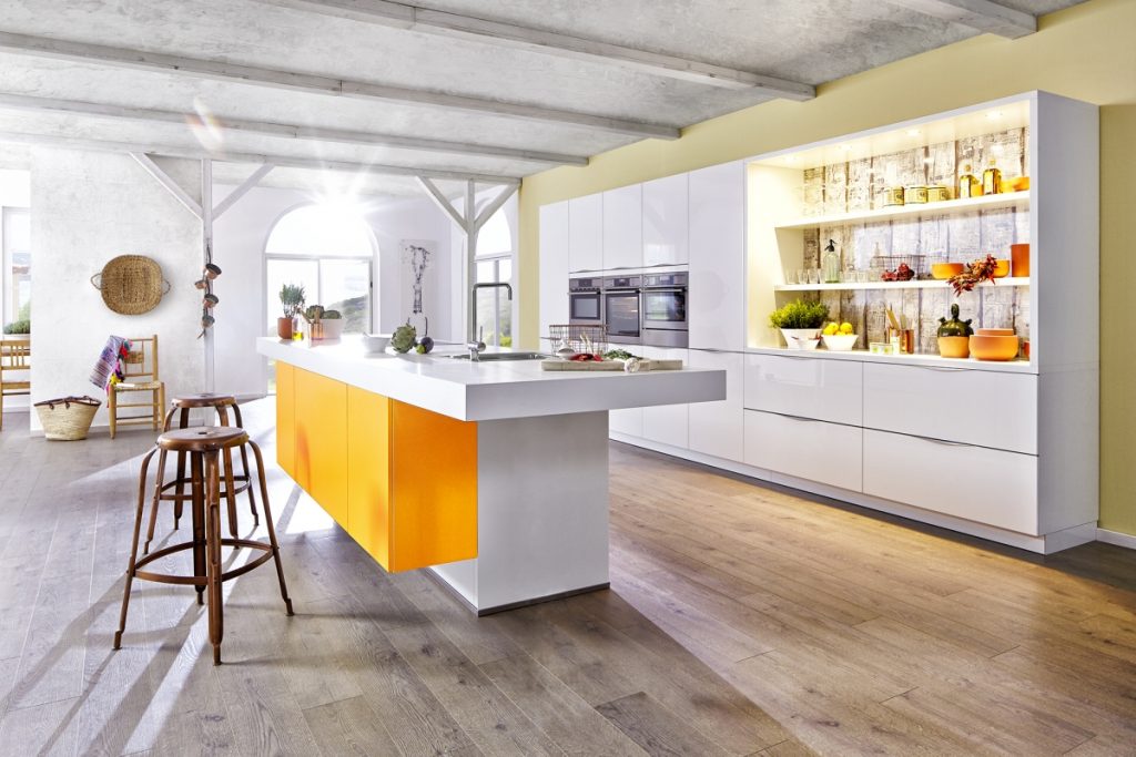 Moderní kuchyně v bílé barvě se žlutými zdi a velkým kuchyňským ostrůvkem. Kuchyně v lesklém provedení.