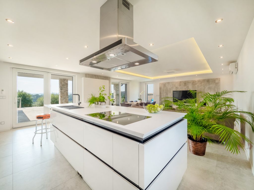 Kuchyňský ostrůvek s digestoří a varnou deskou. Kuchyň propojená s obývacím pokojem.