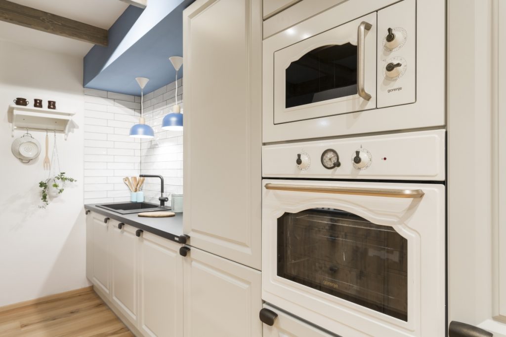 Rustikální kuchyně s spotřebiči v provence stylu v bílé barvě a designovým osvětlením